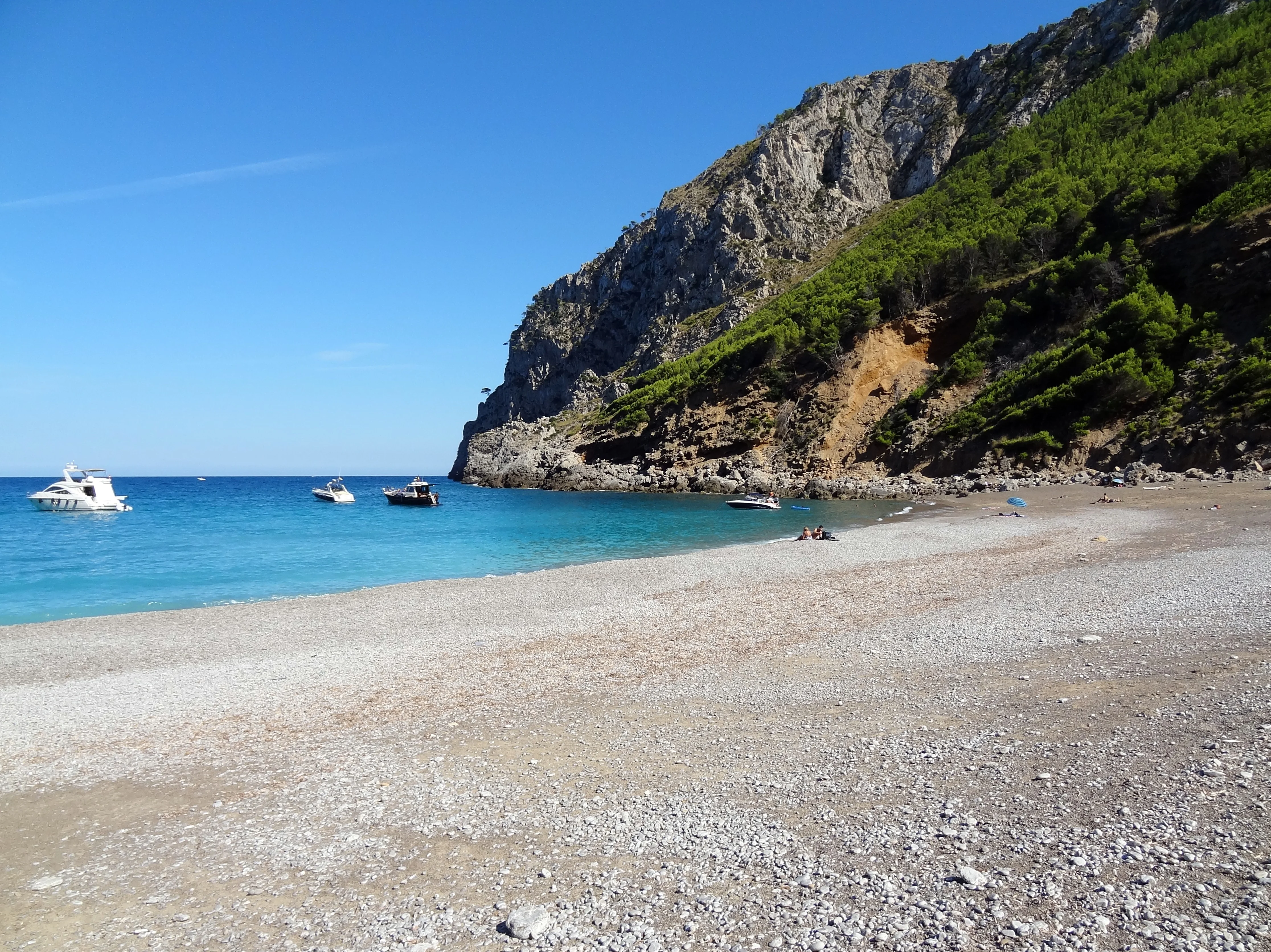The hidden cove of Es Coll Baix with turquoise water and sheer limestone cliffs rising on both sides